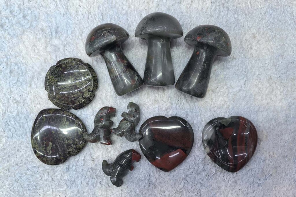 African Bloodstone Meaning represented in carved crystals including mushrooms, hearts, and round shapes
