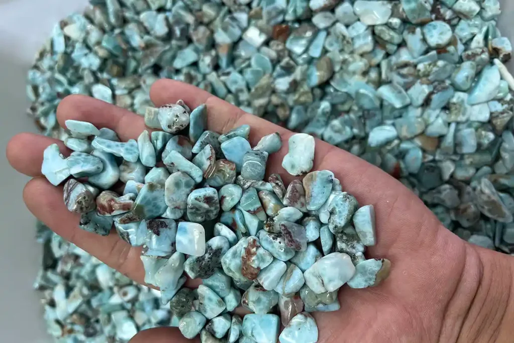 Hand holding larimar chip stones, symbolizing larimar stone benefits