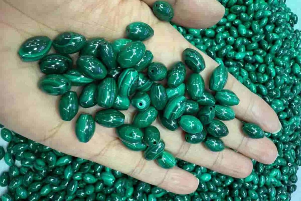 Drop-shaped Malachite beads displayed on hand, showing natural texture and deep green hues that emphasize Malachite benefits for spiritual growth and protection.