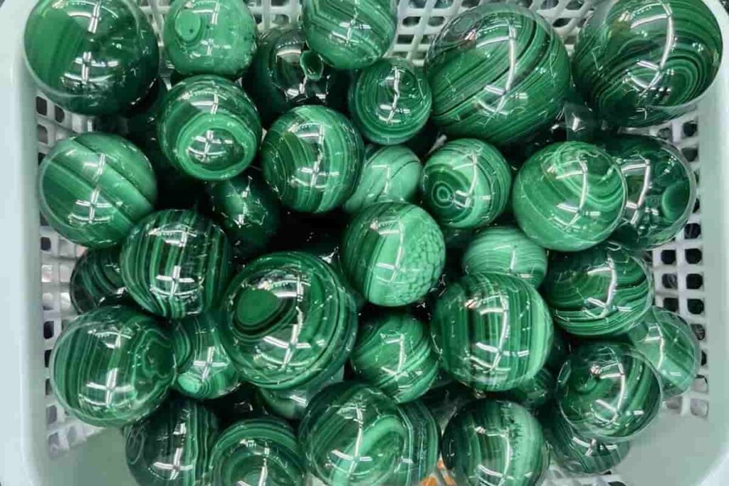 Polished Malachite sphere with concentric green layers, symbolizing Malachite benefits of emotional clarity, transformation, and inner strength.