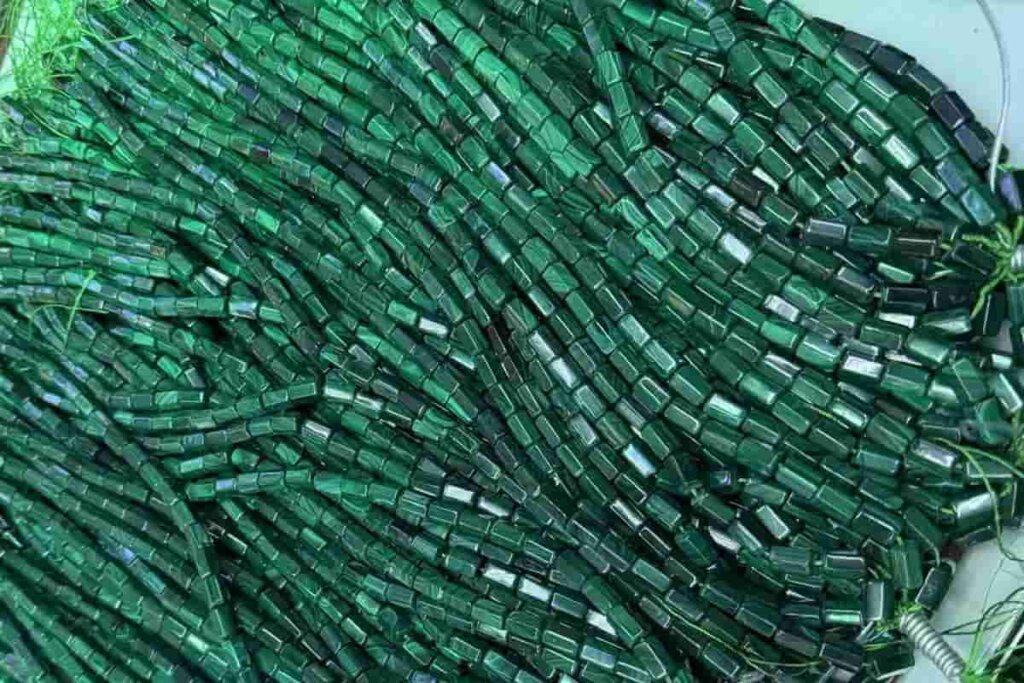 Malachite tube strand beads with linear patterns, admired for Malachite benefits such as grounding energy and promoting emotional balance.