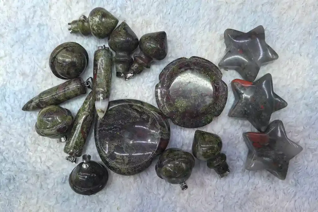 Polished Dragon Bloodstone carvings including round beads, cylindrical shapes, and flat pieces