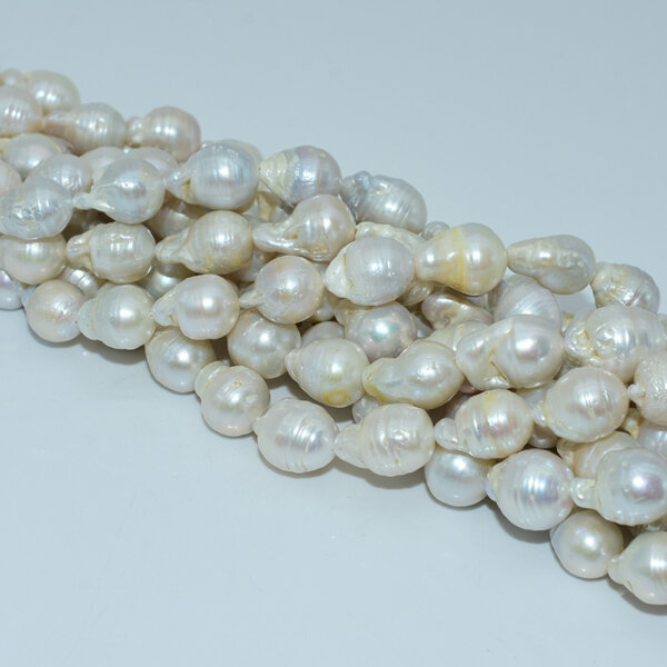 Strands of 13x18mm white baroque pearl beads laid flat on white background
