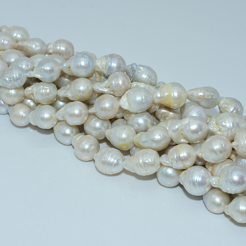 Strands of 13x18mm white baroque pearl beads laid flat on white background