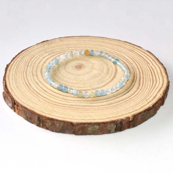 Minimalist wooden jewelry display base with spiral grain pattern, used for gemstone bracelet photography