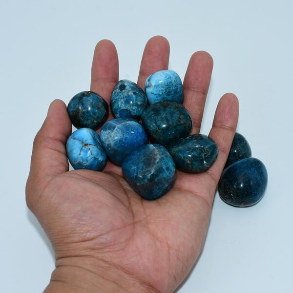 Open palm displaying vivid blue apatite tumbled crystals