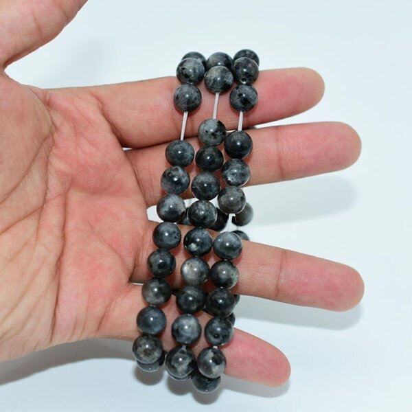 Hand holding two Larvikite Bracelets showcasing natural crystal beads