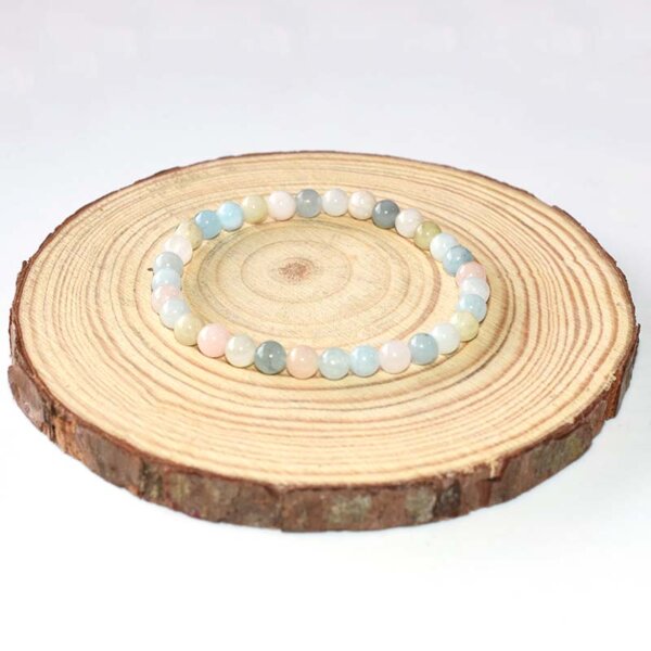 Morganite Crystal Bracelet with light blue and blush beads, neatly arranged on a neutral-toned wood base