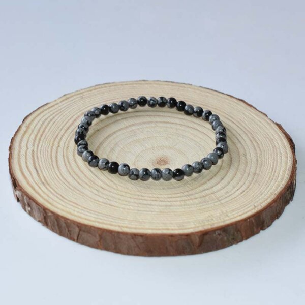 Slim Snowflake Obsidian bracelet laid flat, featuring petite beads and calming protective energy.