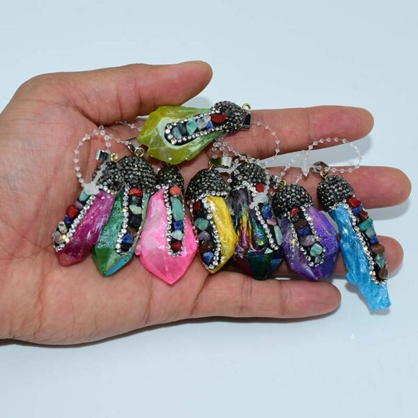 Hand holding assorted colorful chakra crystal pendants