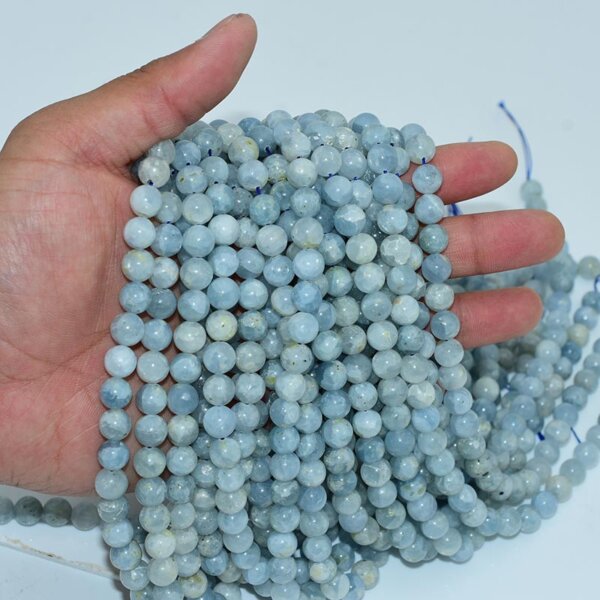 Celestite beads held in palm, showcasing size and natural surface cracks