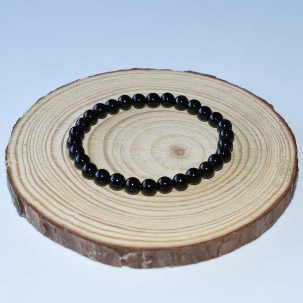 Black tourmaline crystal bracelet presented on rustic wood slice