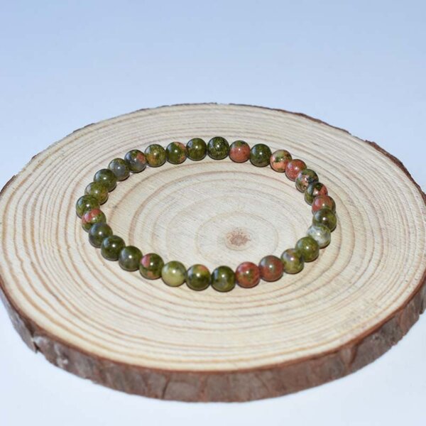 6mm Unakite Bracelet with uniform round beads in muted olive and salmon tones on wood background.