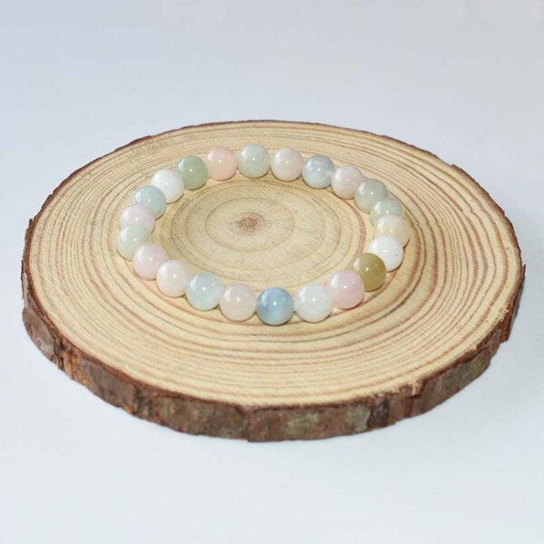 Pale Morganite Bracelet laid on wooden background, soft tone crystal beads in light pink, blue and peach hues