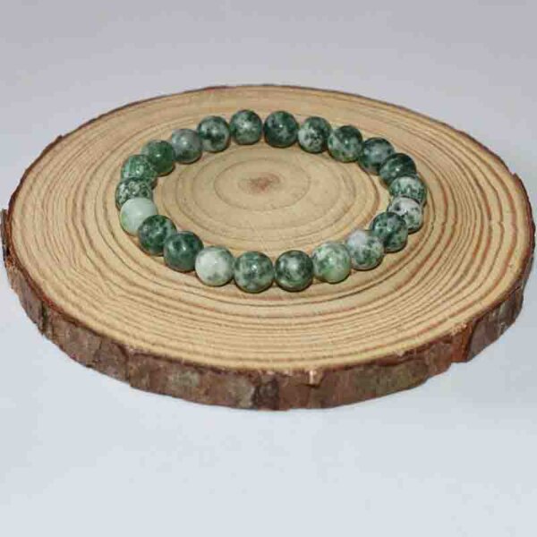 Single loop Green Spot Jasper beaded bracelet on wooden slice background