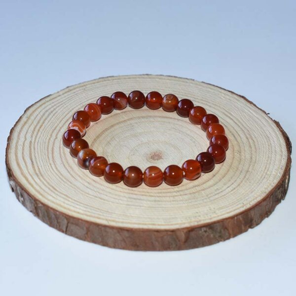 Carnelian bracelet in medium size beads displayed on wood slice