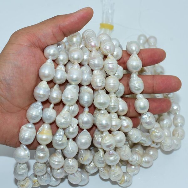 Baroque pearl beads draping from hand, showing irregular shape and luster
