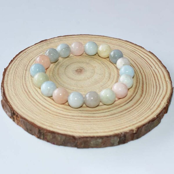 Single Morganite Crystal Bracelet arranged in a circle on natural wood slice, featuring 8mm pink and mint-green beads
