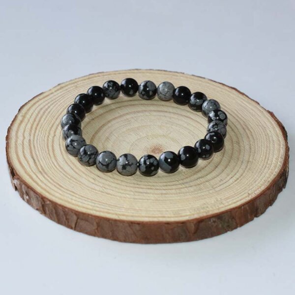 Natural Snowflake Obsidian bracelet displayed on wooden board, crafted for emotional balance and grounding.