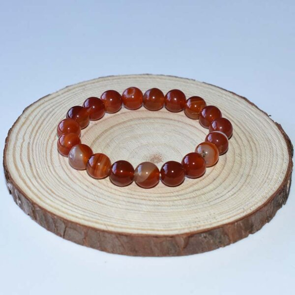Single strand carnelian bracelet with large round beads on wood base