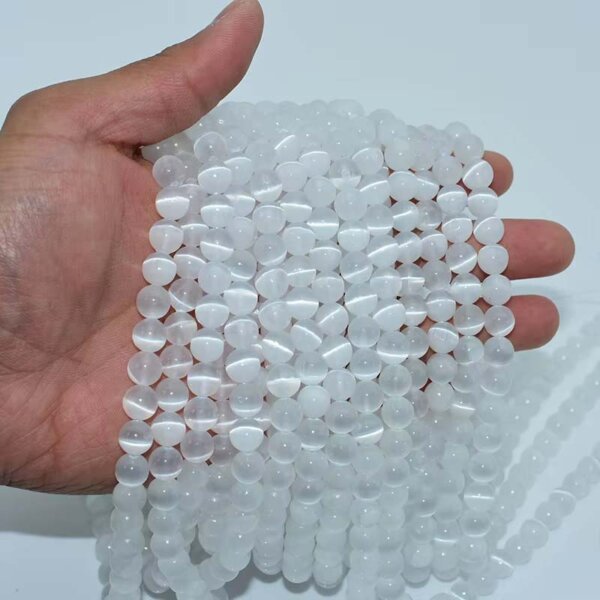 Hand holding strands of polished white selenite crystal beads