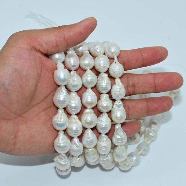Hand holding multiple strands of 13x18mm baroque freshwater pearl beads
