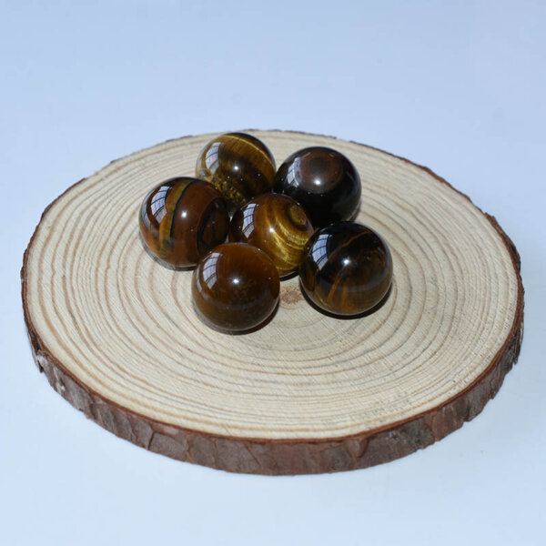 Tiger Eye crystal spheres displayed on a wooden tray, natural light photography