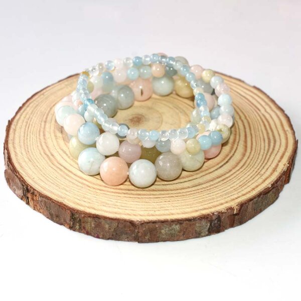 Stacked Morganite Crystal Bracelets displayed on round wooden board, soft pastel gemstone beads in elastic setting