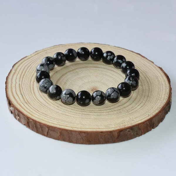 Snowflake Obsidian bracelet with large round beads on wooden background, ideal for bold crystal energy.