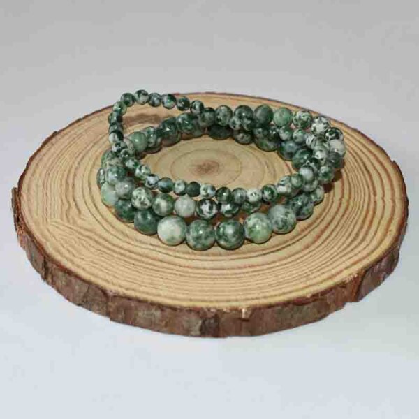 Double loop Green Spot Jasper bracelet displayed on wooden slice