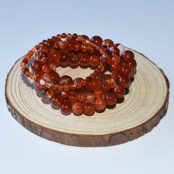 Multiple carnelian bracelets stacked on wooden display platform