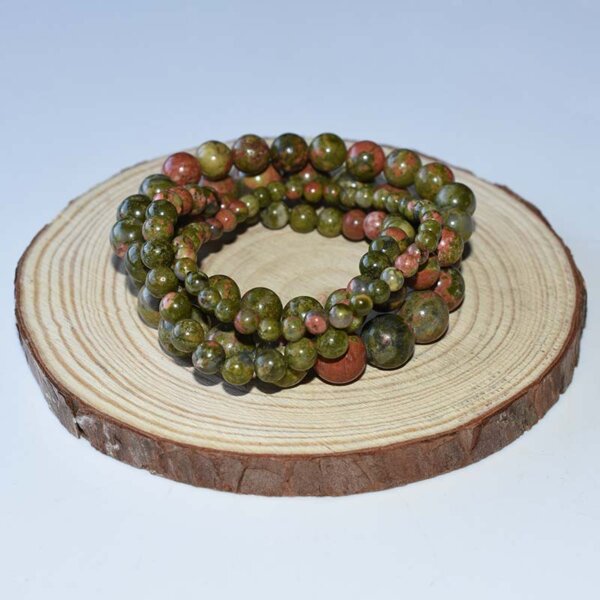 Unakite Bracelets coiled on wood display, highlighting polished bead texture and earthy tones.