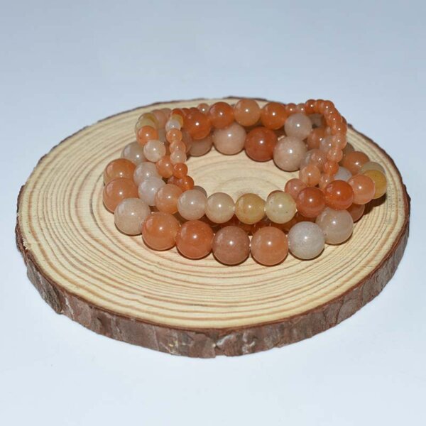 Stacked Red Aventurine Bracelets on wood slice, mixed tones of red and orange