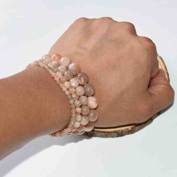 Layered Sunstone Crystal Bracelets worn on wrist, natural peach-orange beads, stacked crystal jewelry style