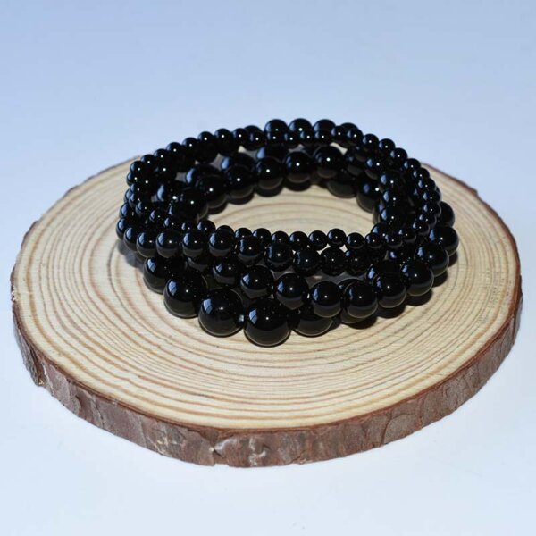 Black tourmaline bracelet displayed in spiral shape on wooden base