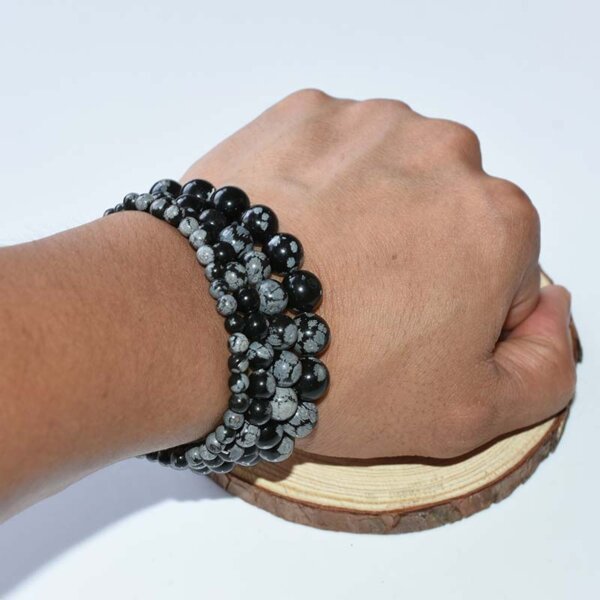 Snowflake Obsidian bracelets stacked on wrist, showcasing layered crystal style for grounding and clarity.