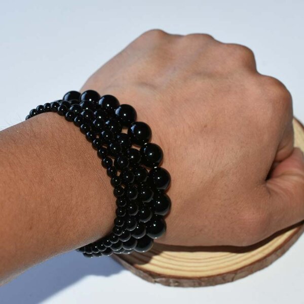 Person wearing layered black tourmaline bracelets on wrist