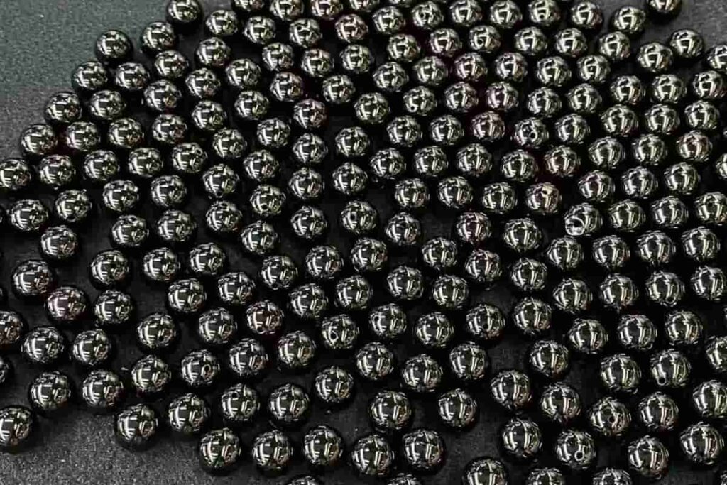 Smooth Black Tourmaline beads displayed on black cloth, highlighting deep color and energy associated with Black Tourmaline meaning.