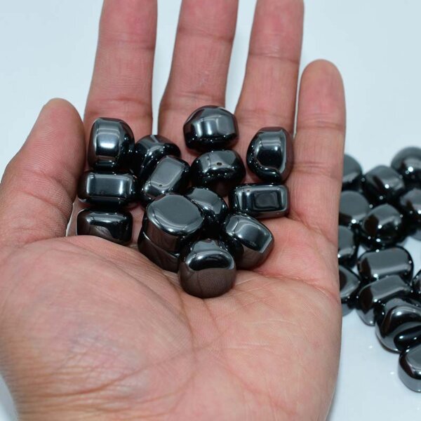 Close-up of Tumbled Hematite stones held in palm – smooth grounding crystals