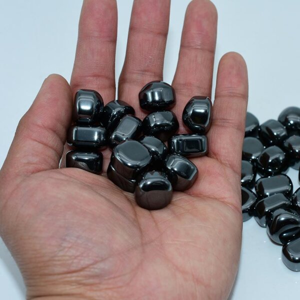 Tumbled Hematite stones in hand – 15–30mm polished crystals for grounding