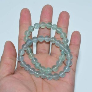 Hand holding multiple Blue Fluorite Bracelets for size comparison