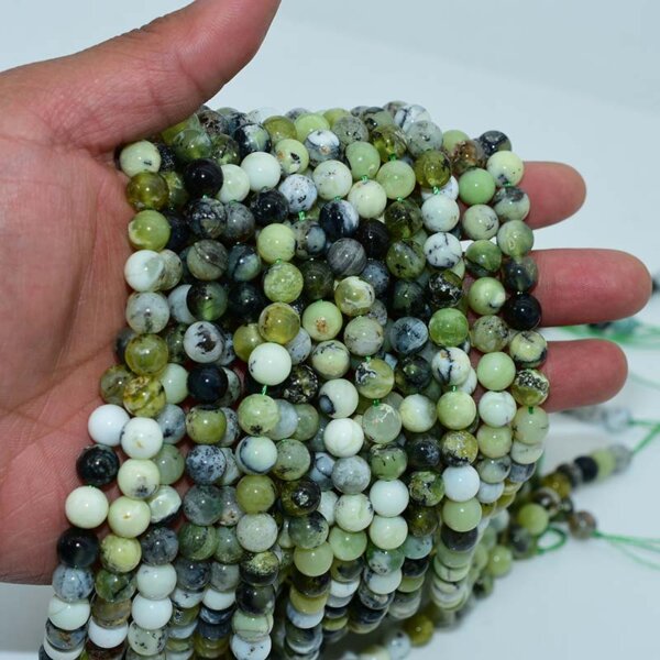 Hand displaying multiple strands of Green Opal Beads in assorted sizes