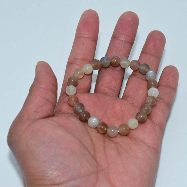Peach Moonstone Bracelet held in hand showing full strand and color variation