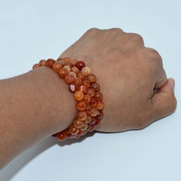 Wrist wearing stacked Dragon Vein Agate Bracelets in warm orange tones