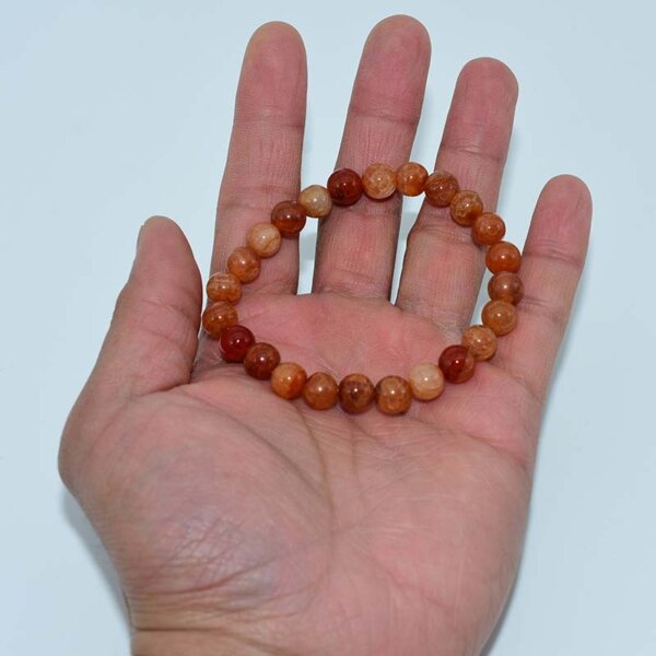 Hand holding a Dragon Vein Agate Bracelet made with orange crackled beads