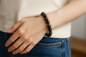 Close-up of a woman wearing a Pietersite Bracelet with swirling blue and gold beads on her wrist