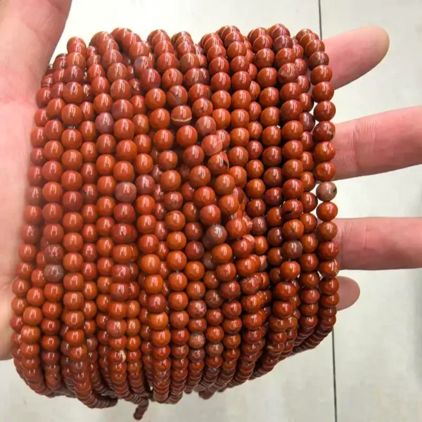 Hand holding natural Red Jasper Stone Beads, showing authentic texture and vibrant red color of gemstone beads