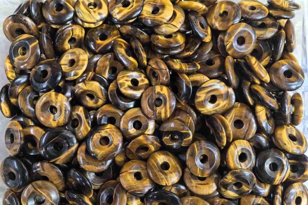 Tiger Eye Benefits illustrated by round donut-shaped tiger eye beads for grounding energy