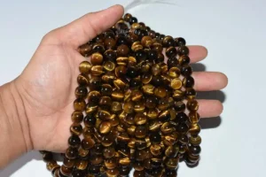 Hand holding Authentic Tiger Eye Beads strands with golden luster