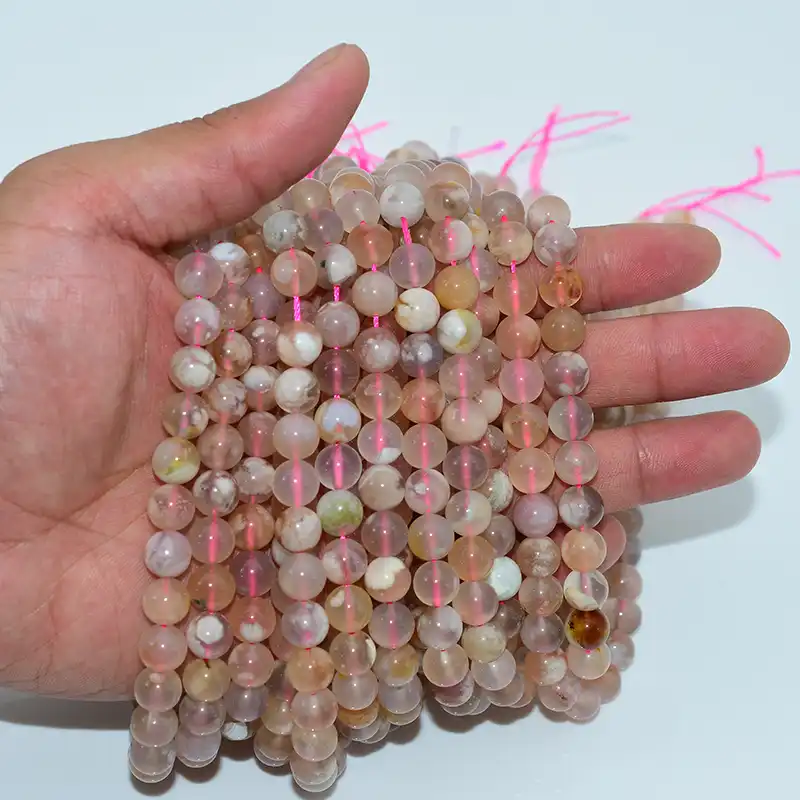 8mm flower agate beads displayed on hand showing natural pink tones and floral inclusions for wholesale jewelry making.